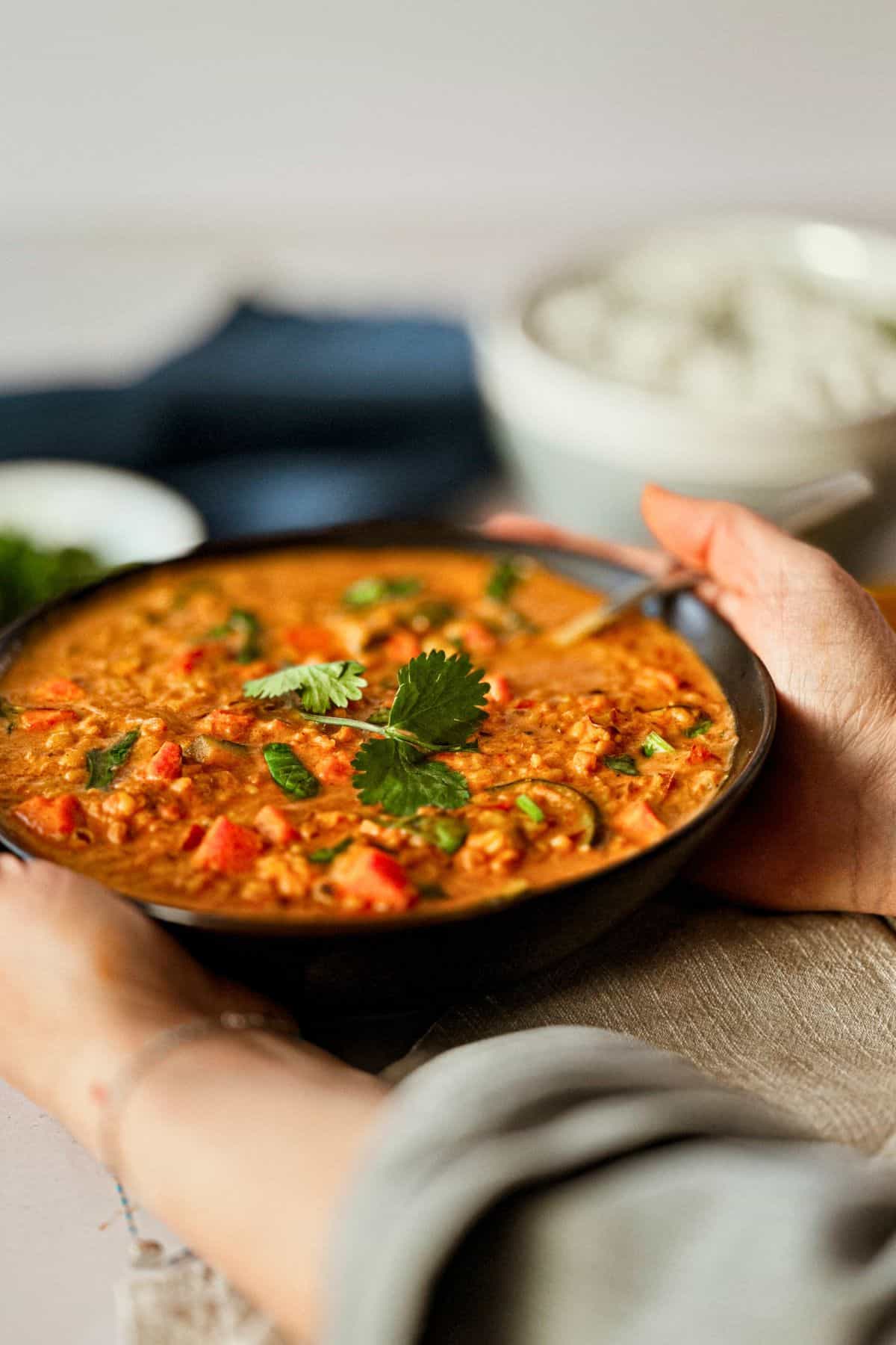 hands holding split mung bean curry bowl
