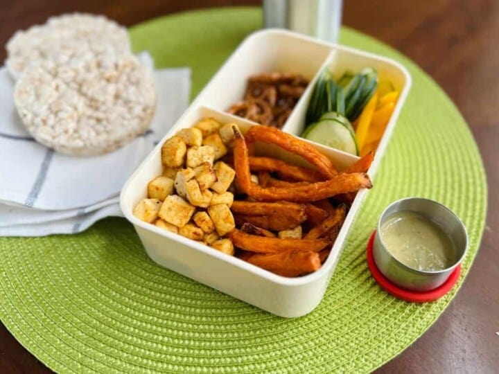 tofu and sweet potato fries in a lunchbox with pretzels, yellow peppers, and cucumbers