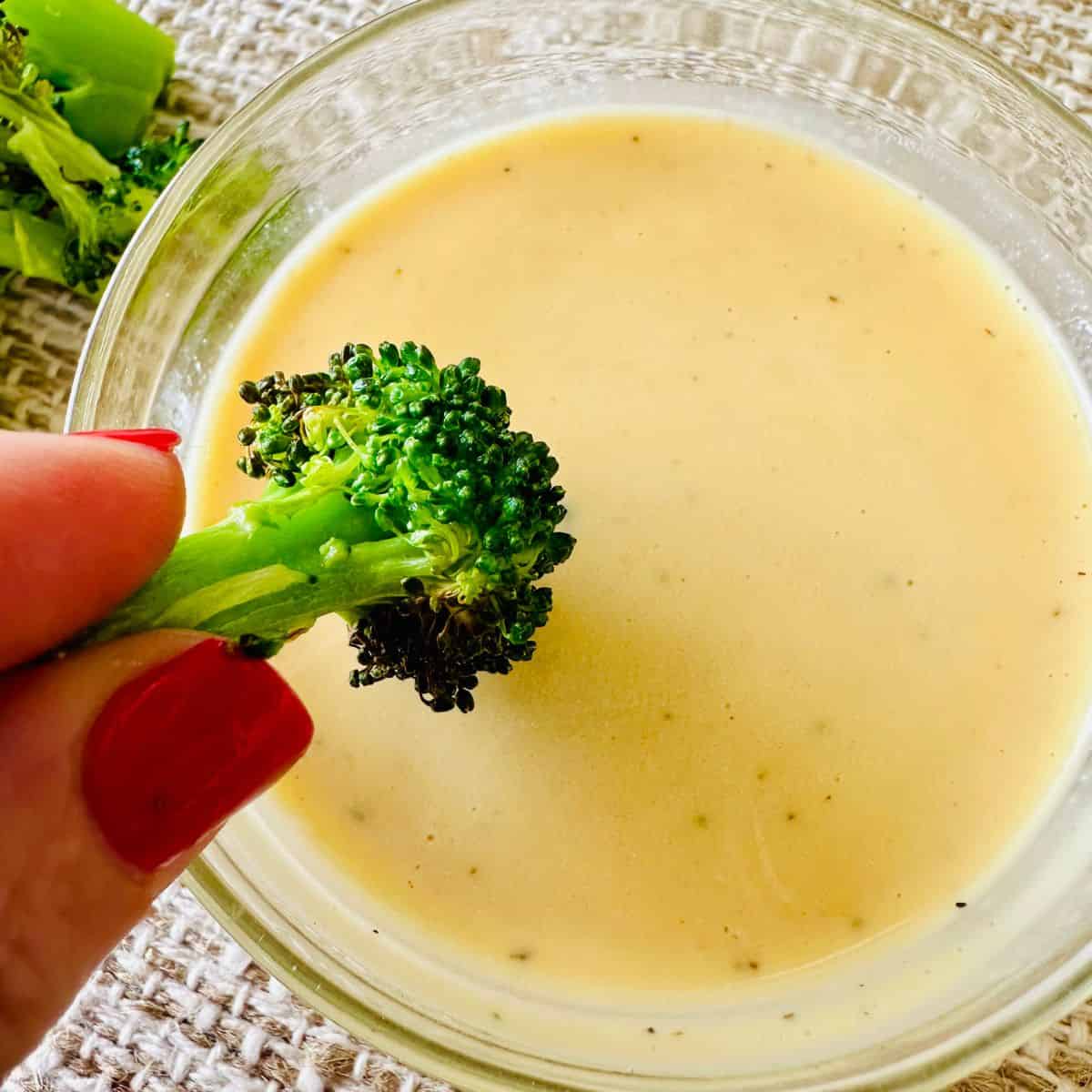 broccoli being dipped into vegan honey mustard
