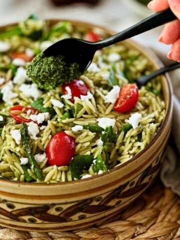 vegan orzo sunflower seed pesto salad in a bowl with a spoonful of pesto floating on top