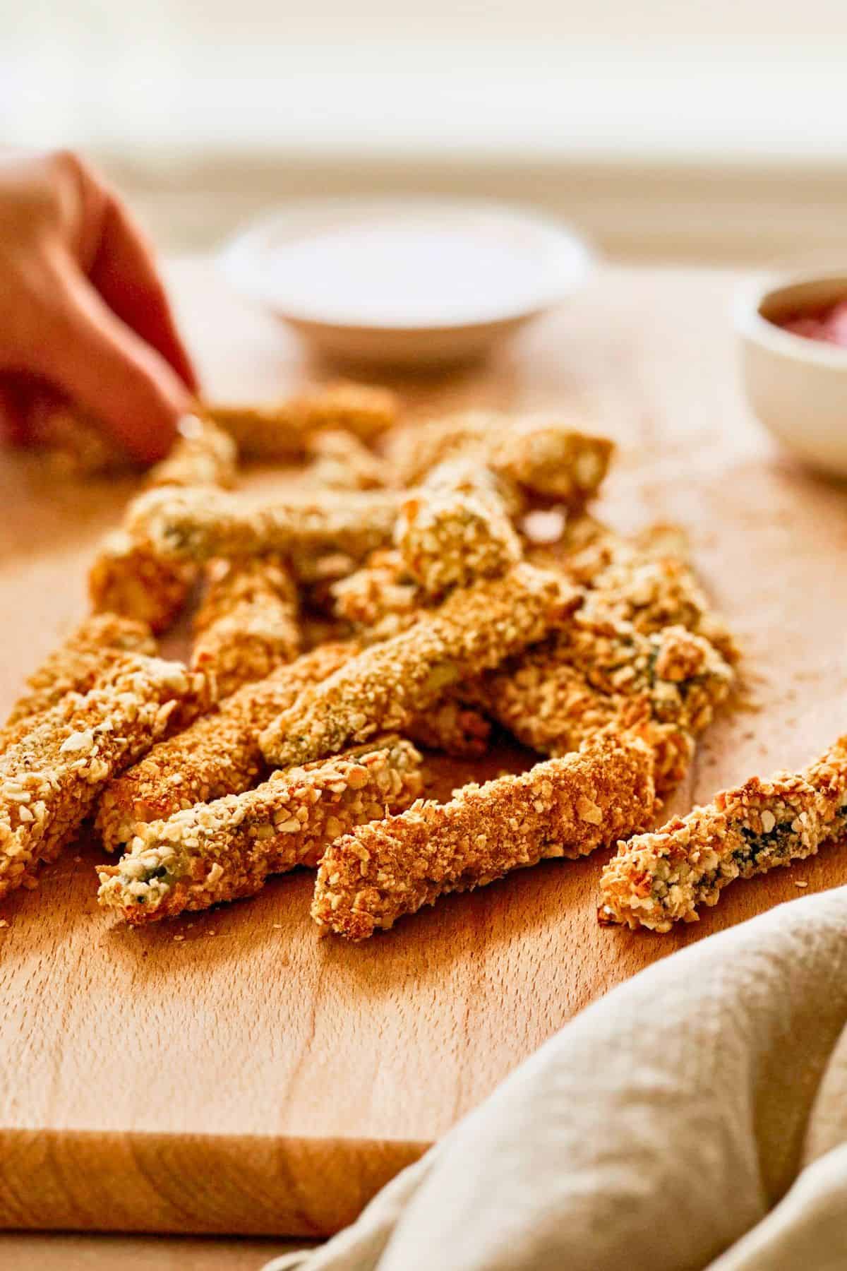 side view of vegan panko baked zucchini fries on a cutting board