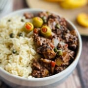 Vegan picadillo with white rice in a bowl topped with three green olives