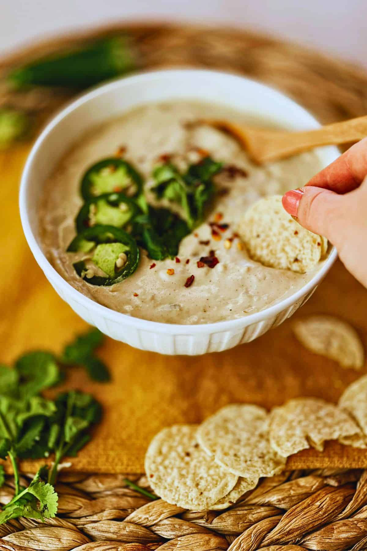 chip dipping into vegan white queso dip (or queso blanco) in a bowl