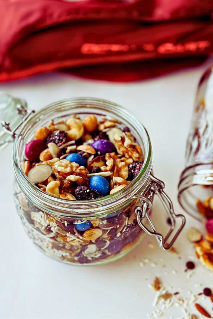 vegan trail mix with unreal chocolate gems in glass container; side view