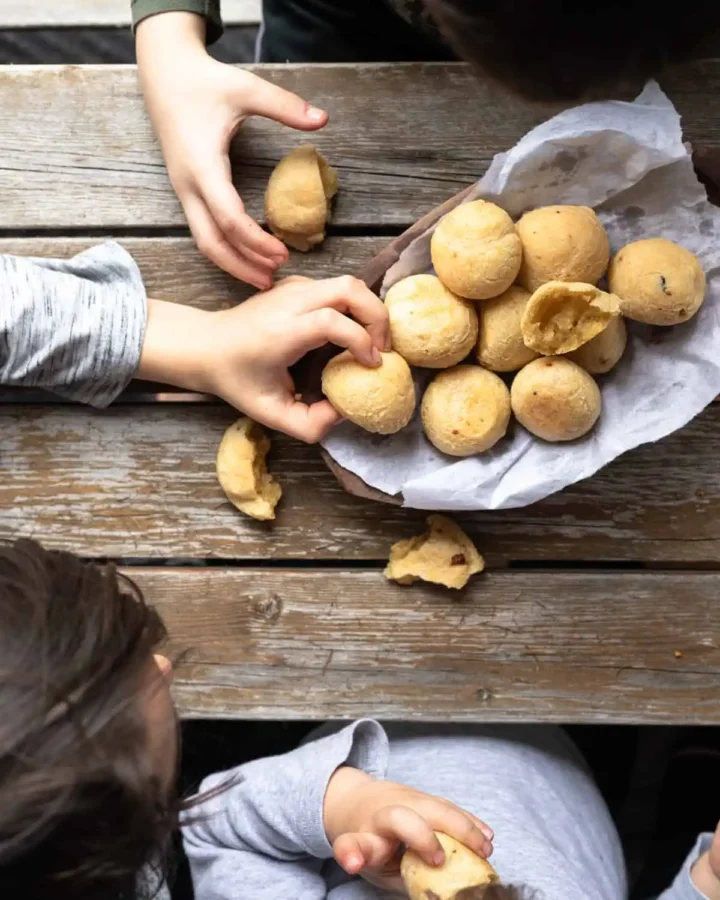 pao de quijo on a plate with children grabbing the bread
