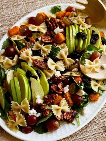 autumn pasta salad on a platter with wooden serving spoons. top view.