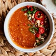 overhead pic of easy Thai Peanut Sauce in a bowl with garnishes of scallions, red chili peppers, and crushed peanuts.