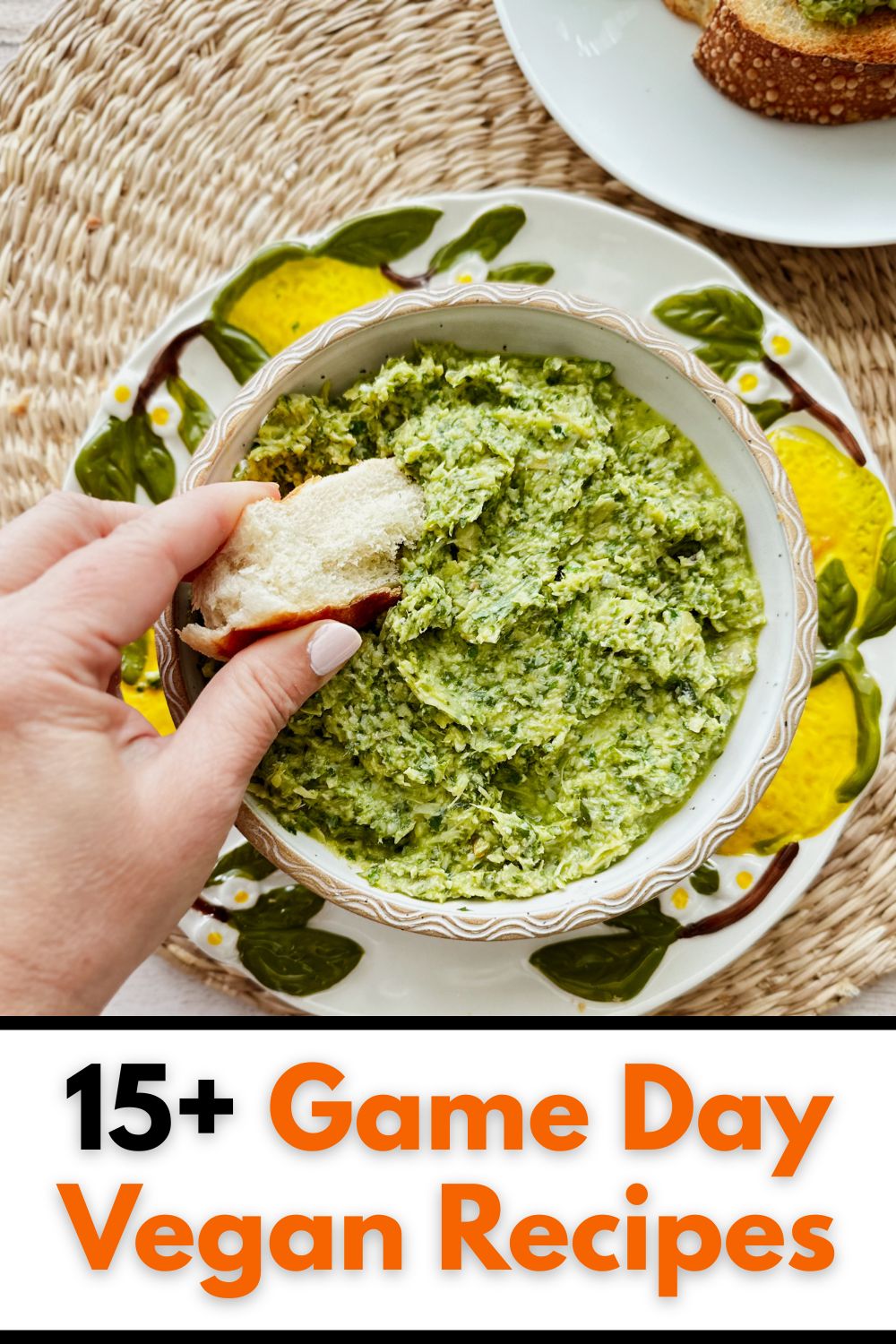 Hand dipping a piece of crusty bread into a bowl of creamy green vegan spinach artichoke dip, with text overlay reading "15+ Game Day Vegan Recipes."