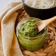 thai basil pesto in a small mason jar with a wooden spoon scooping some up.