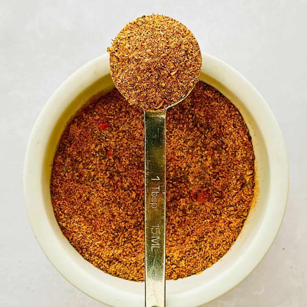 vegan chicken seasoning in a bowl with a measuring spoon on top.
