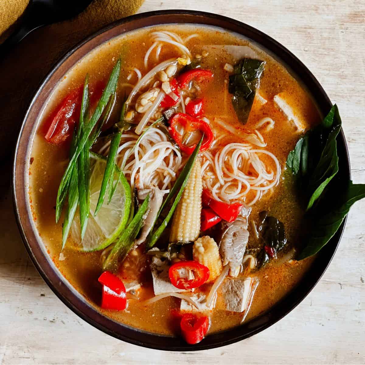 top view of vegan Tom Yum Noodle Soup in a bowl.