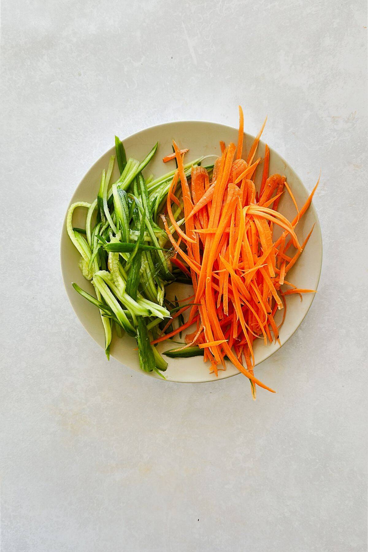 shredded carrots and cucumbers on a plate.