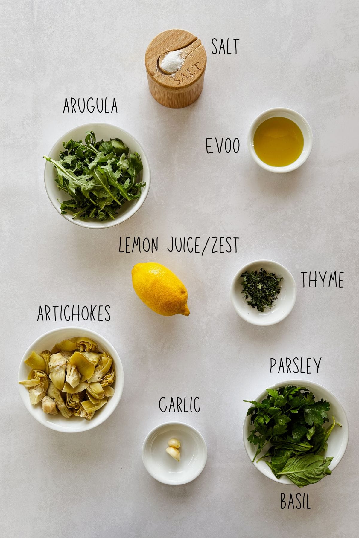 Ingredients for lemony arugula artichoke dip: fresh arugula, canned artichokes, lemon, garlic, basil, parsley, thyme, extra virgin olive oil, and salt.