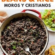 A red Dutch oven of Cuban black beans and rice with peppers and herbs, served with plantains and salad. Text reads “Cuban Black Beans & Rice.”