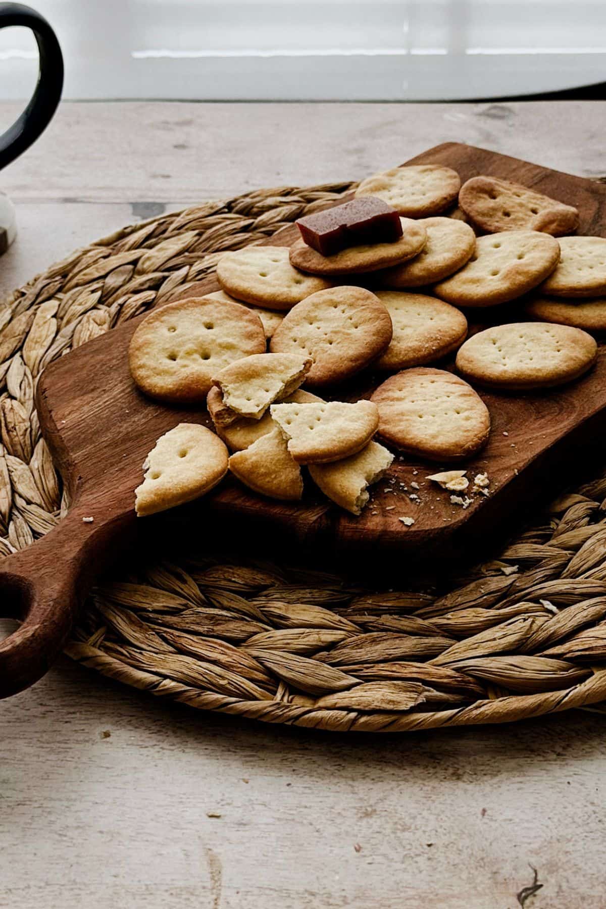 Cuban crackers on a wooden board, some cracked open to show their crisp texture, and a few with guava paste pieces on top.