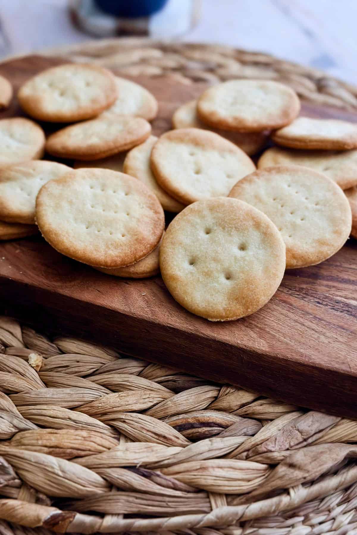 A close-up of baked Cuban crackers stacked on a wooden board, highlighting their golden color and light puff.