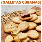 Pin image with text that reads “How to Make Cuban Crackers (Galletas Cubanas)” over a photo of golden, flaky homemade Cuban crackers stacked on a wooden board, one topped with guava paste.