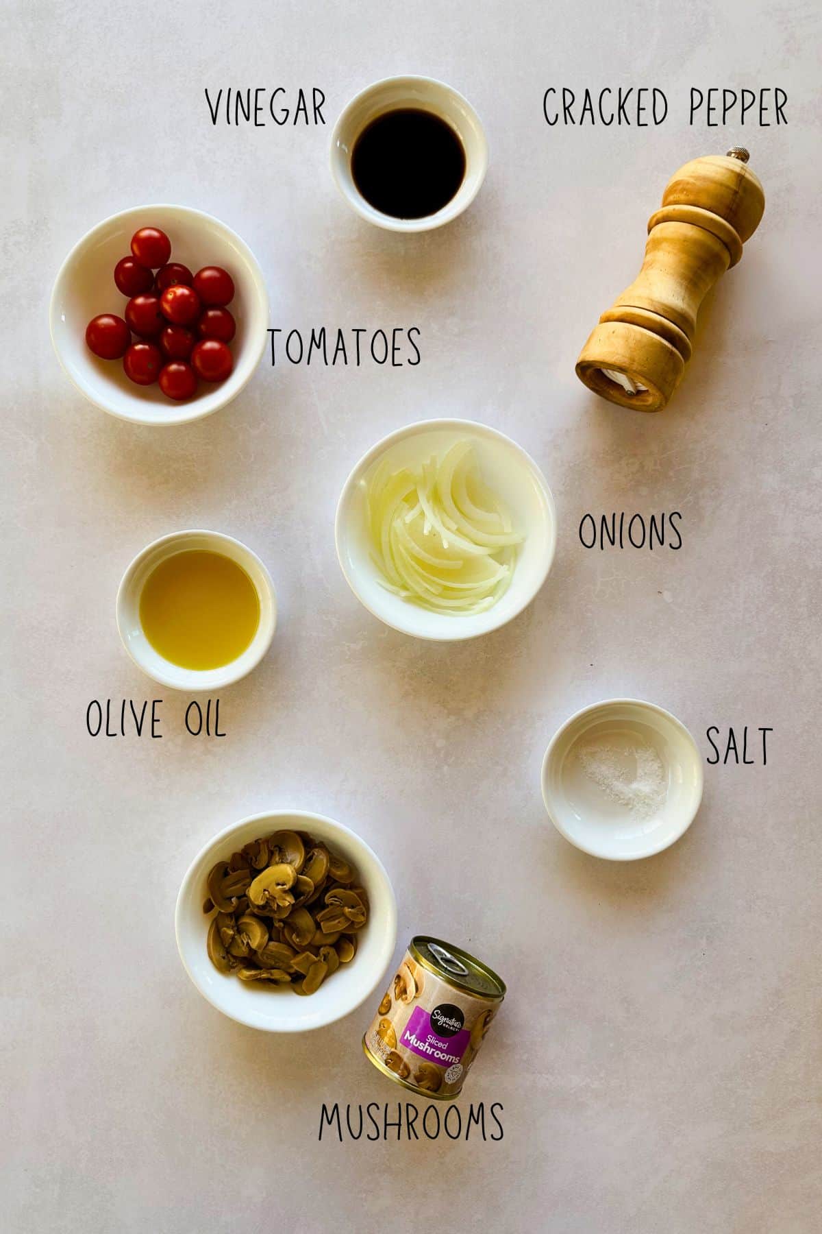Labeled ingredients for Easy Mushroom Salad: canned mushrooms, sliced onions, cherry tomatoes, olive oil, vinegar, salt, and cracked black pepper.