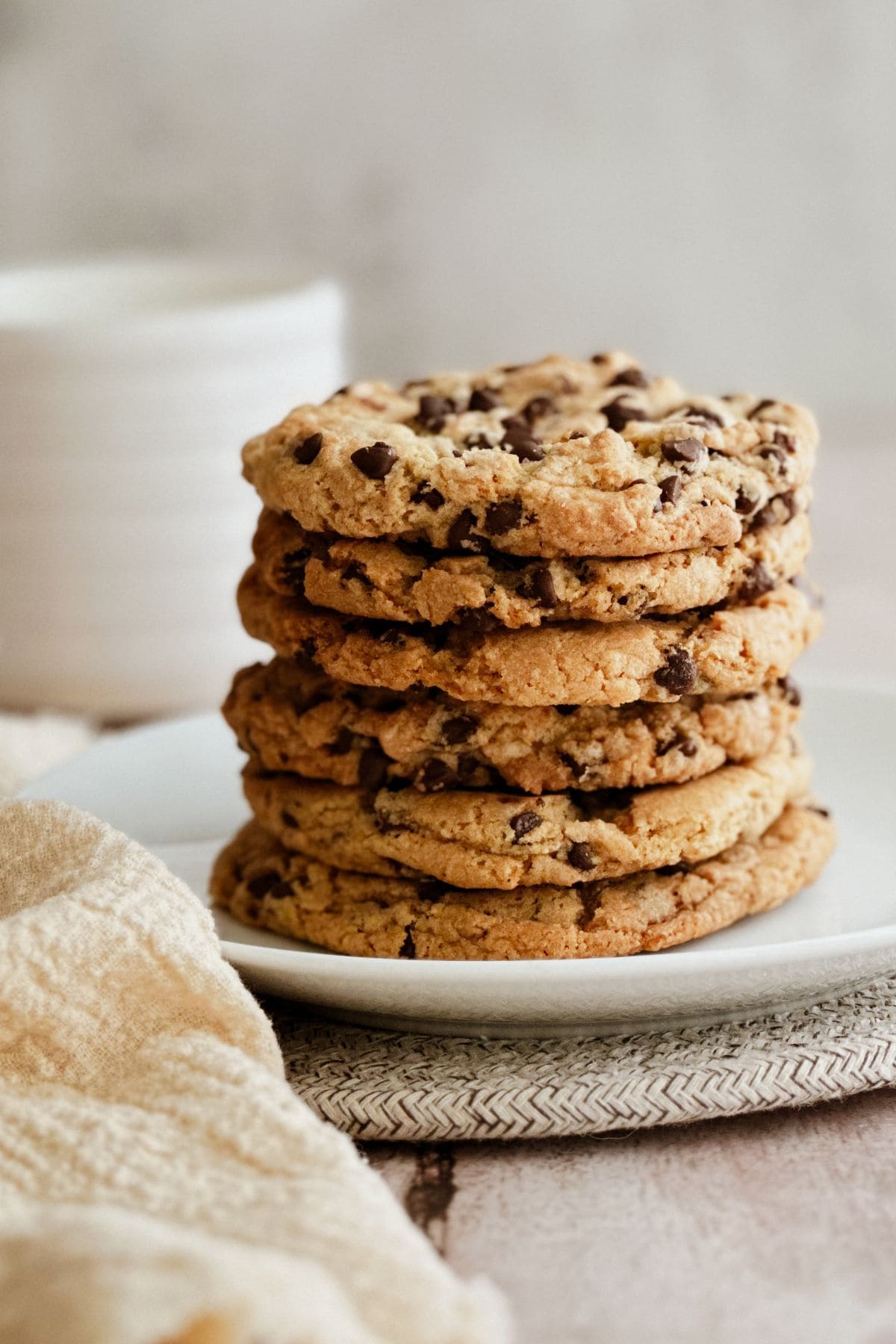 Stack of thick vegan chocolate chip cookies on a white plate.