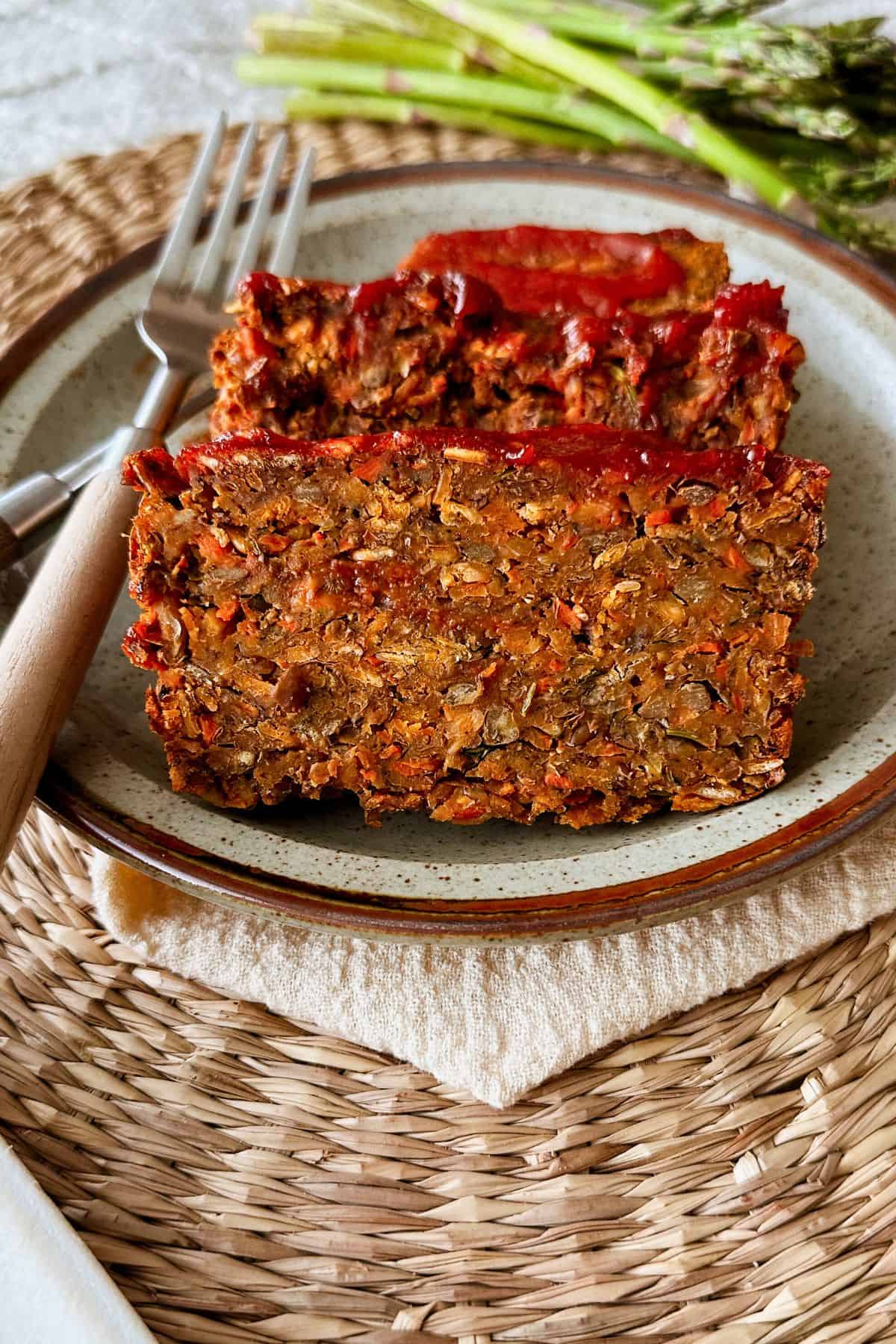 Close-up of sliced vegan lentil loaf showing a hearty, textured interior of lentils and vegetables, brushed with a sweet-tangy glaze.
