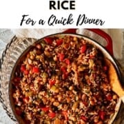 Text reading “How to Make Skillet Beans & Rice for a Quick Dinner” above a red skillet filled with rice, beans, peppers, and onions.