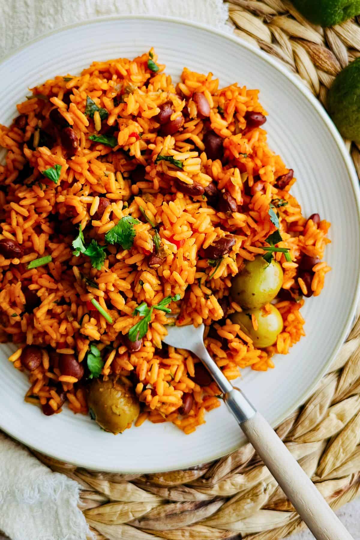 Top view of a plate of Puerto Rican Yellow Rice with a fork in the rice. 