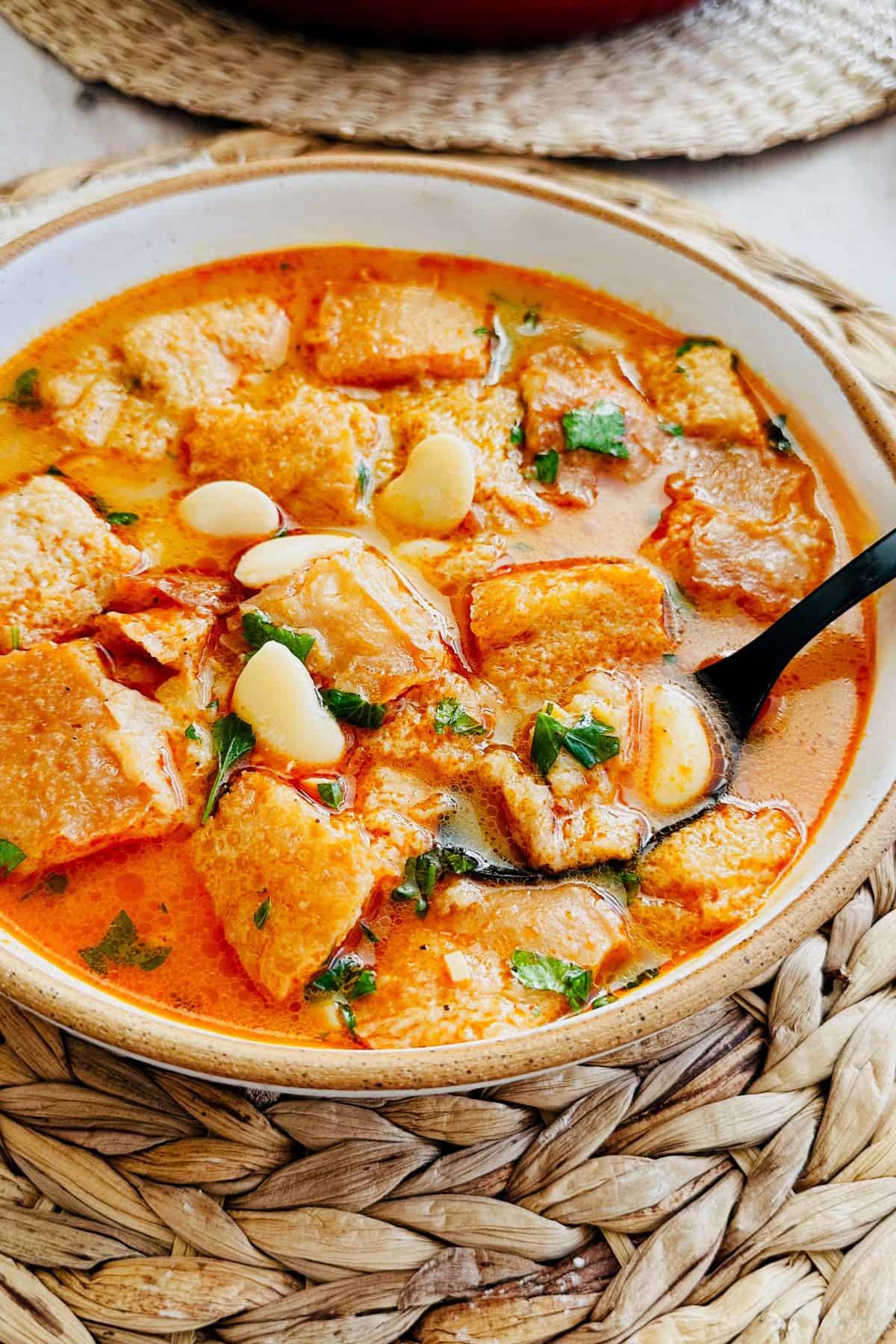 Spanish garlic soup garnished with butter beans, parsley, and olive oil, served hot in a ceramic bowl.