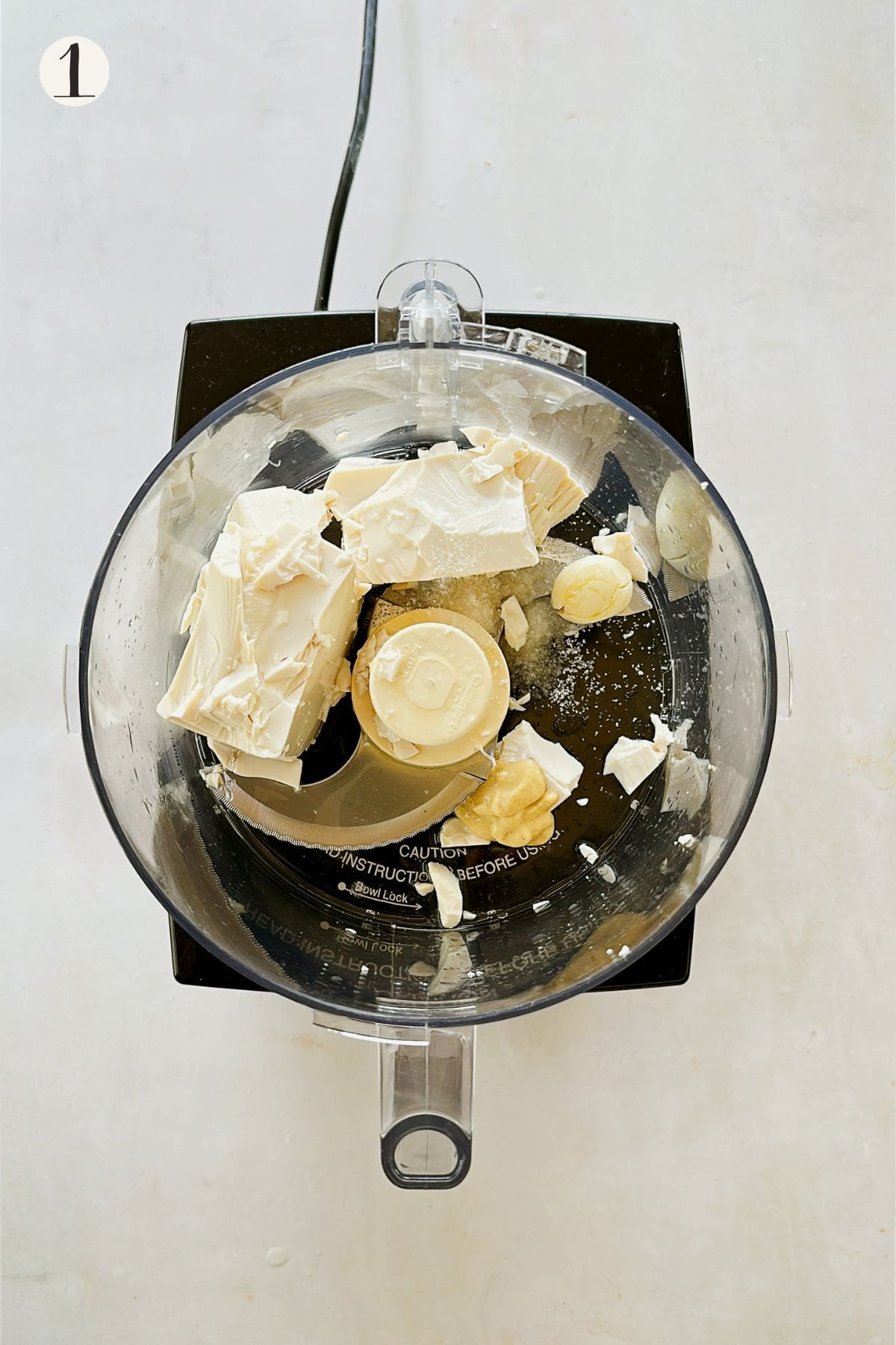 Silken tofu, garlic, mustard, vinegar, oil, and salt added to a food processor to begin making vegan tofu mayo.