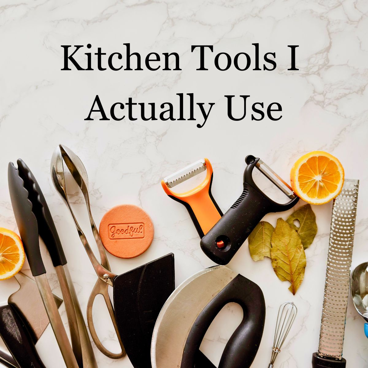 Flat lay of everyday kitchen tools including tongs, scissors, peelers, a microplane zester, and a mini whisk on a white marble surface with halved oranges and bay leaves, with text overlay reading "Kitchen Tools I Actually Use."