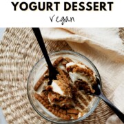 Pinterest graphic for Overnight Biscoff Yogurt Dessert vegan recipe showing softened Biscoff cookies and creamy yogurt being scooped with two black spoons in a glass bowl on a woven placemat.