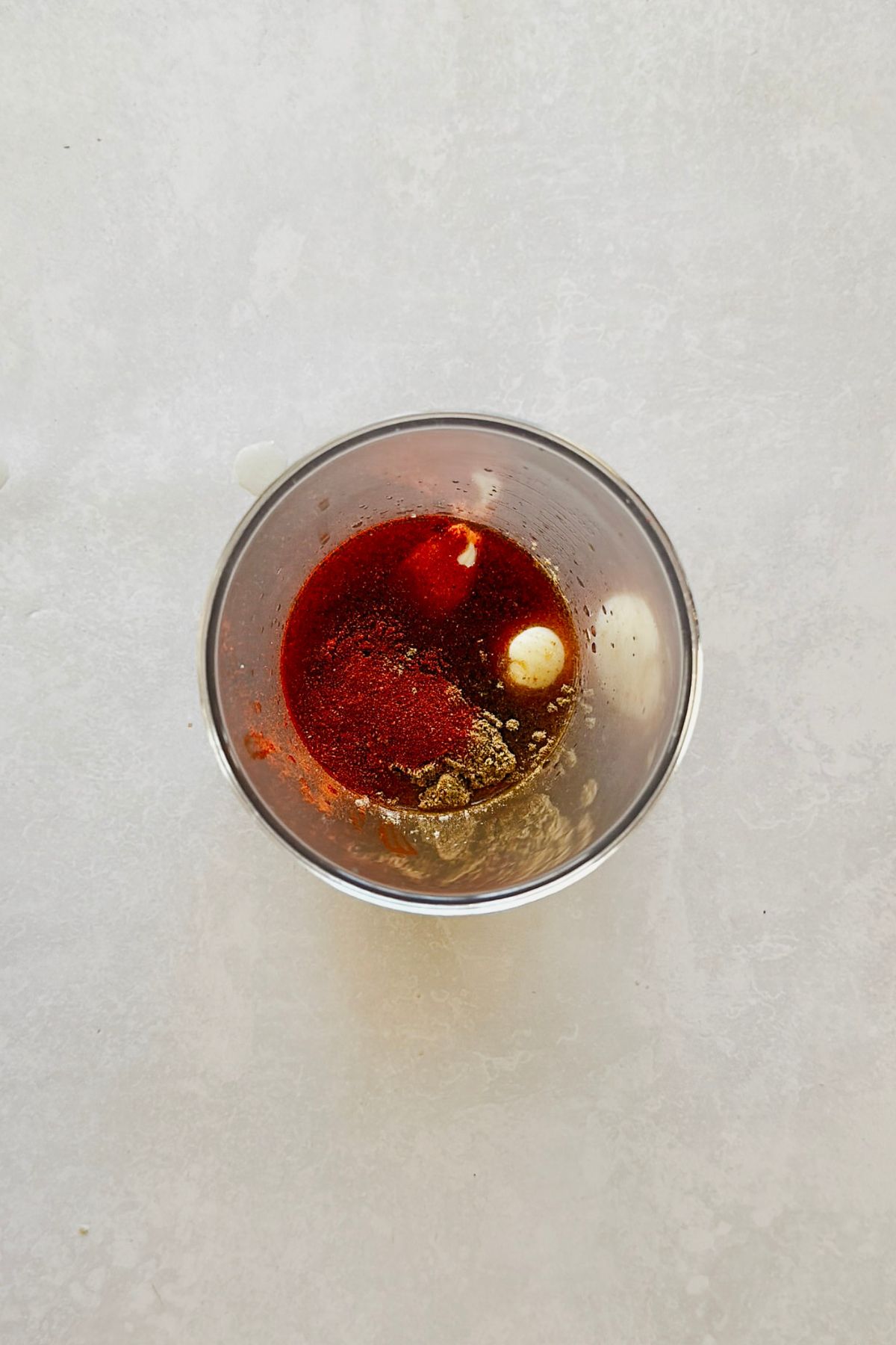 An immersion blender cup filled with red wine vinegar, maple syrup, chipotle pepper, smoked paprika, cumin, and garlic, ready to be blended into chipotle vinaigrette.