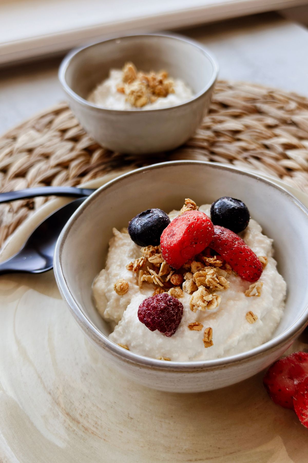 Bowl of thick vegan Greek yogurt topped with granola and mixed berries.