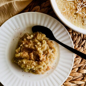 Boniatillo con coco topped with shredded coconut and cinnamon in a white bowl, with the serving dish in the background.