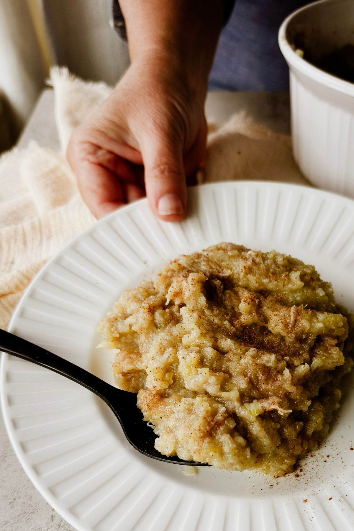 Hand holding a plate of boniatillo con coco, dairy-free Cuban sweet potato and coconut pudding