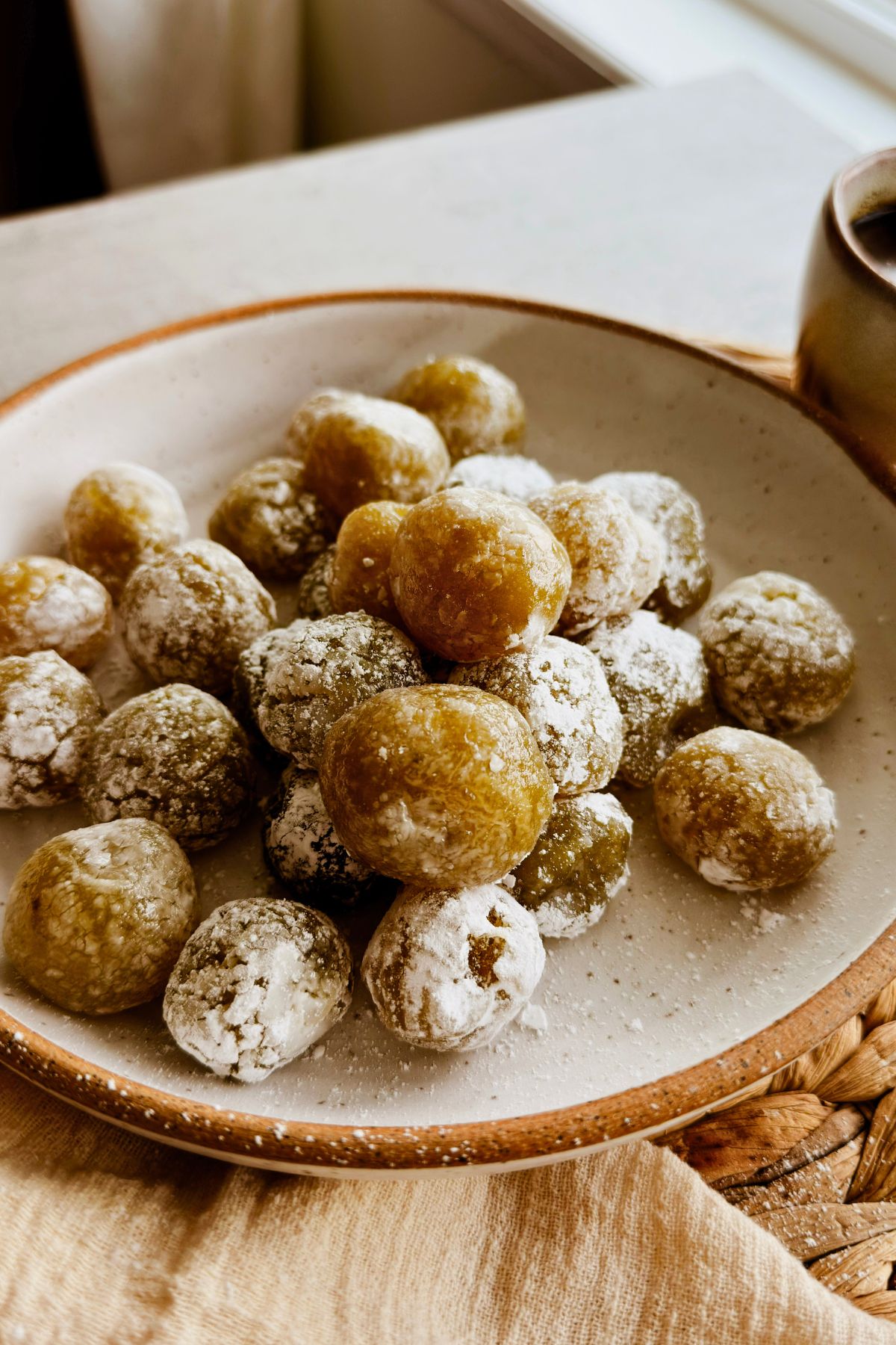 Boniatillo seco, Cuban sweet potato candy balls dusted with powdered sugar, piled on a speckled plate with coffee alongside.