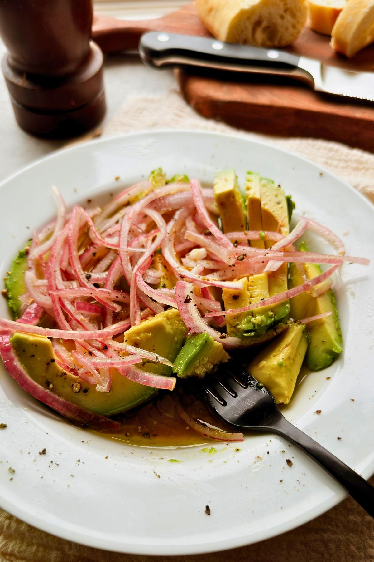 Cuban avocado salad with red onion and a fork, with sliced bread in the background.