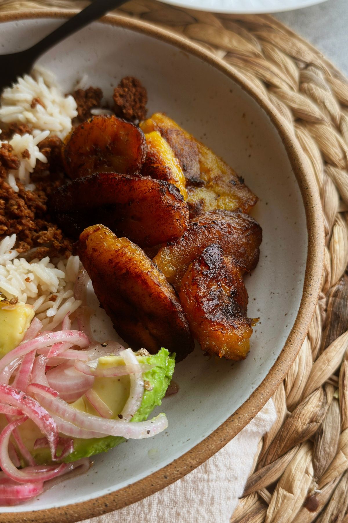 Plátanos maduros served with rice, vegan picadillo, avocado, and pickled red onions