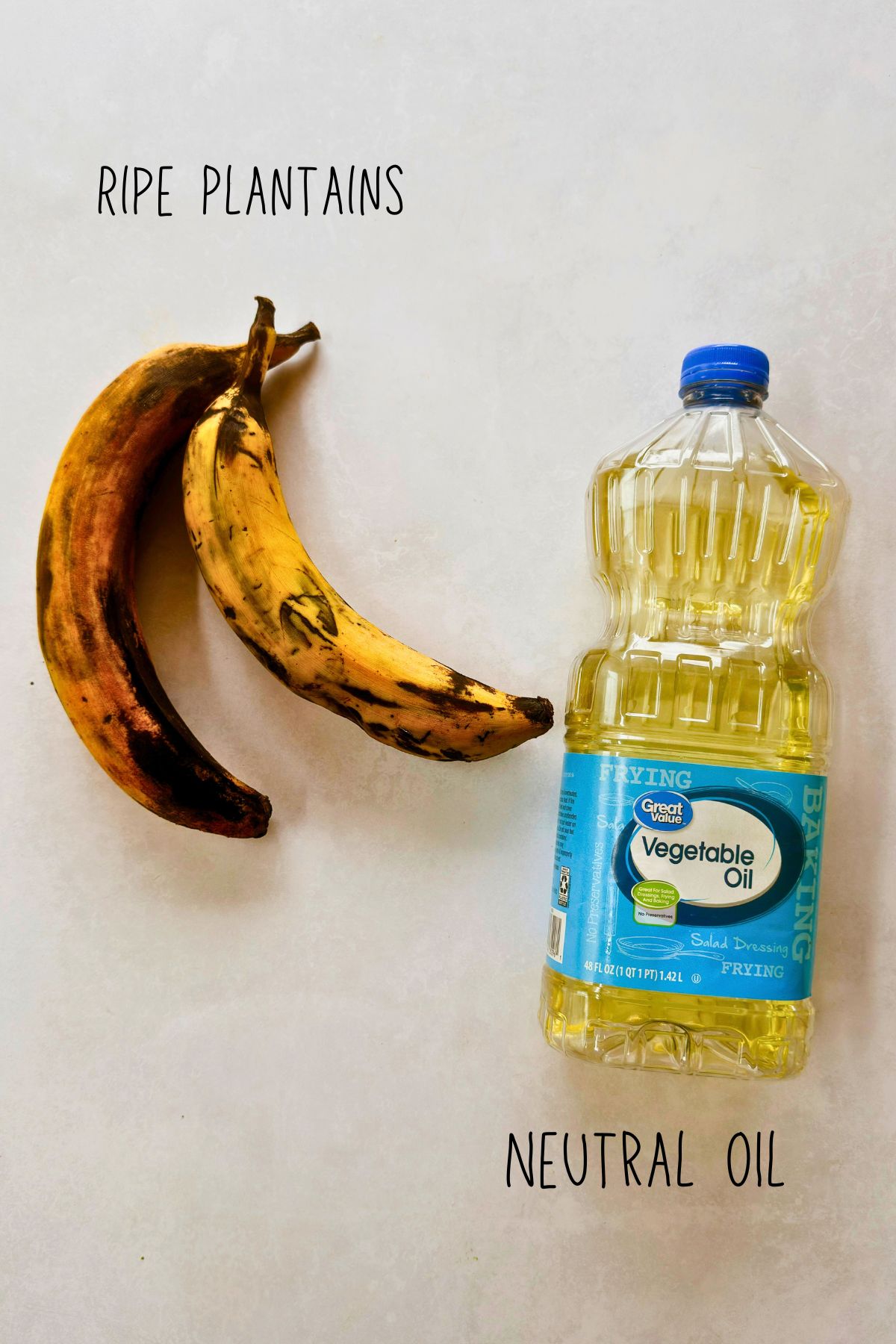 Two very ripe plantains beside a bottle of neutral vegetable oil