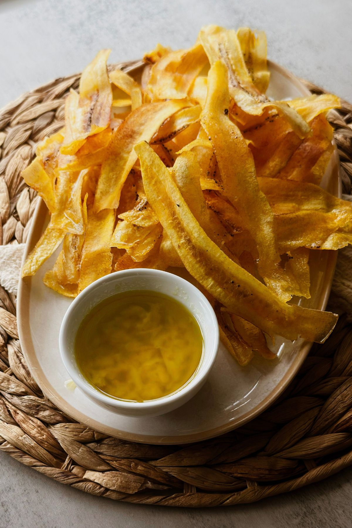 Crispy mariquitas served on a plate with a bowl of garlicky mojo.