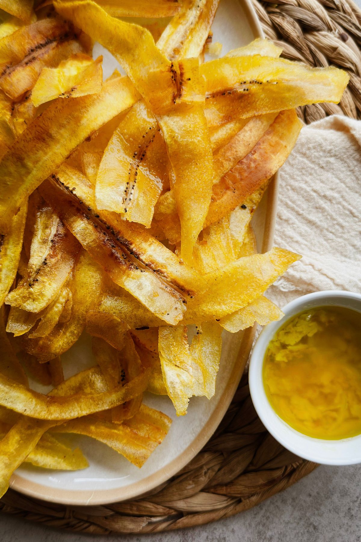 Close-up of crispy mariquitas beside a small bowl of garlicky mojo.