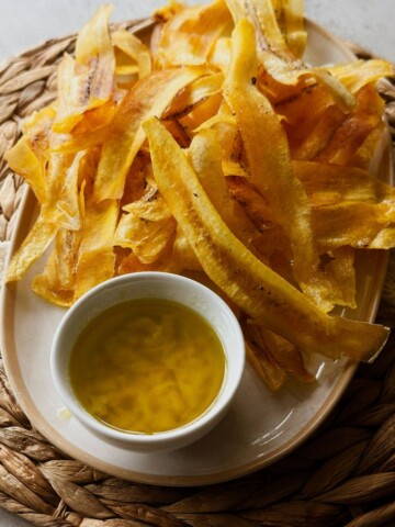 Crispy mariquitas served with garlicky mojo on a woven placemat.
