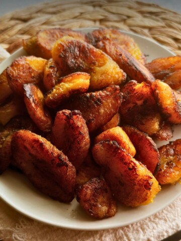 Caramelized plátanos maduros on a white plate.