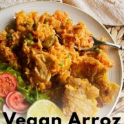Plate of vegan arroz con pollo with tostones, salad, and a lime wedge, with text overlay reading How to Make Vegan Arroz Con Pollo.