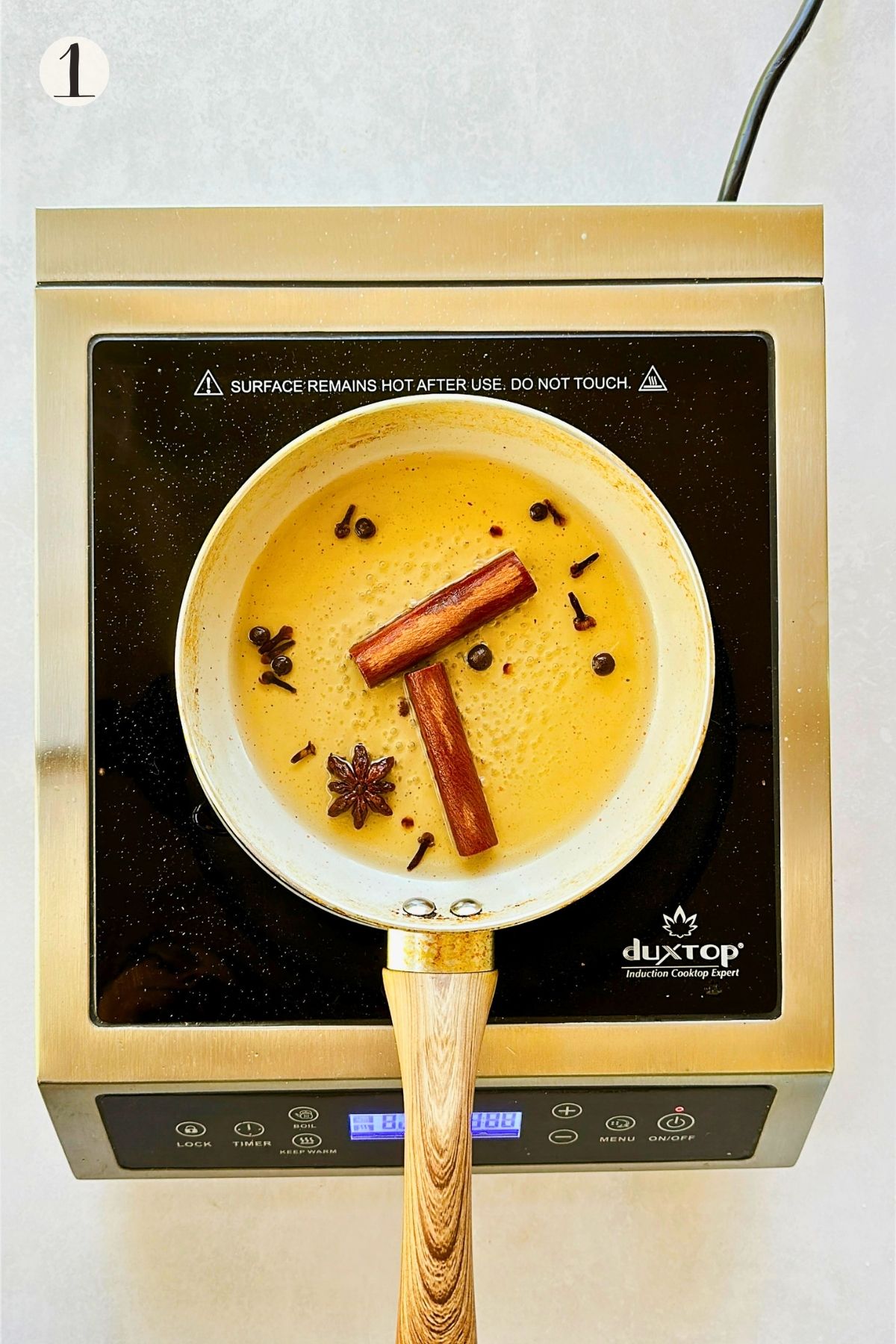 Step 1: Cinnamon sticks, whole cloves, star anise, and allspice simmer in amber-colored water in a saucepan.