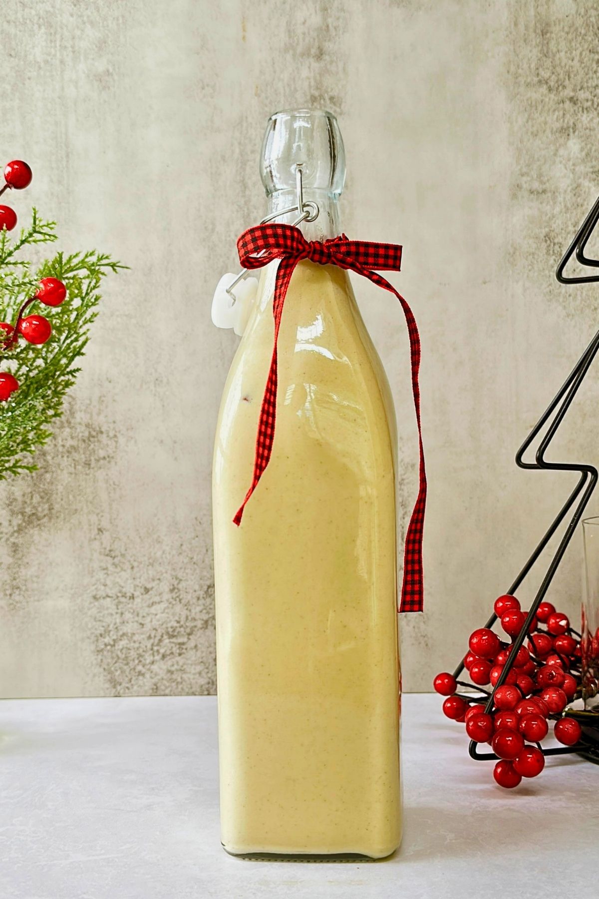 Swing-top bottle of vegan crema de vie tied with a red plaid ribbon for holiday gifting.